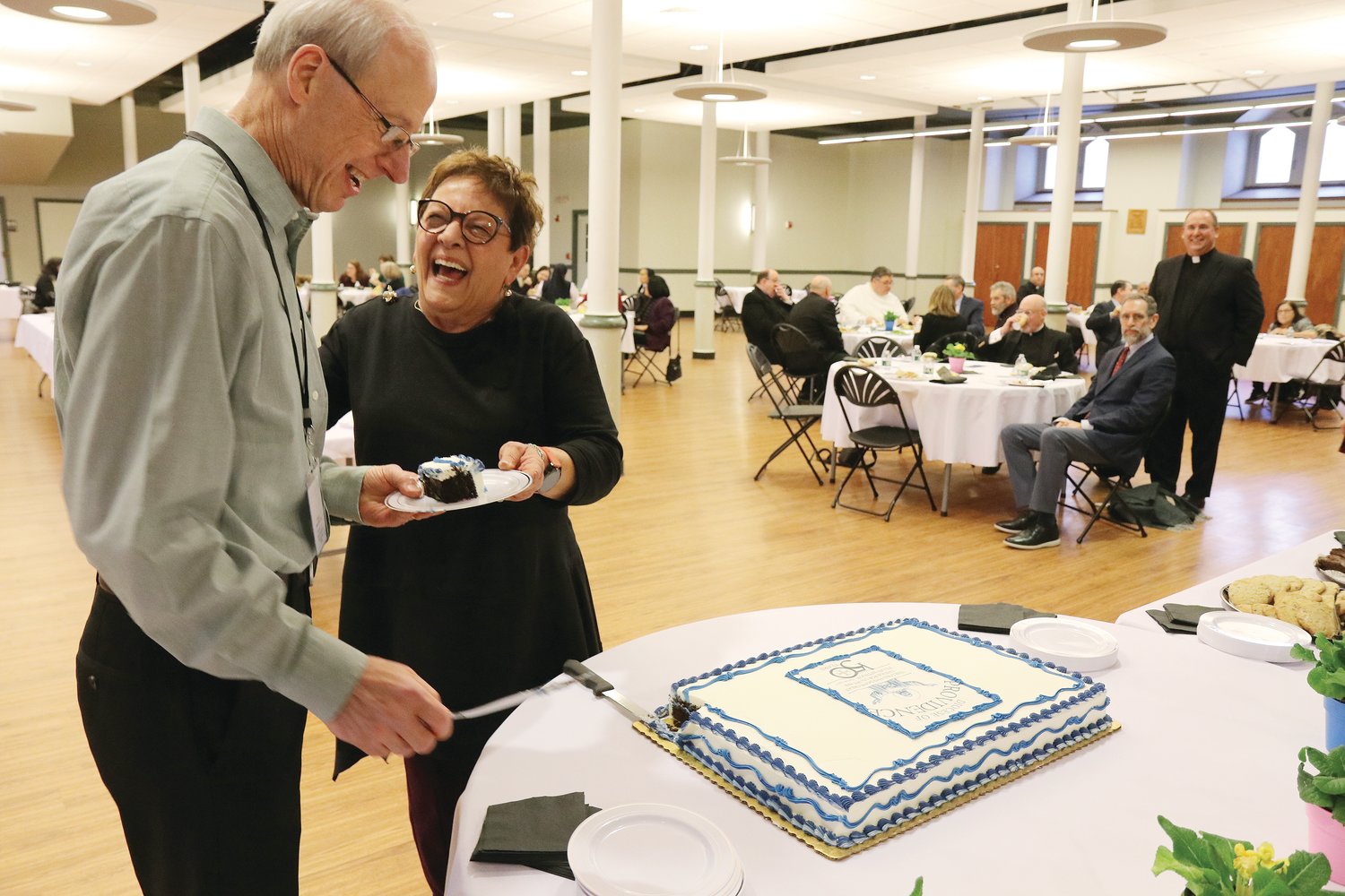 The longest and shortest serving employees cut the anniversary cake at the luncheon.